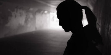 Depressed sad young female standing in a dark tunnel