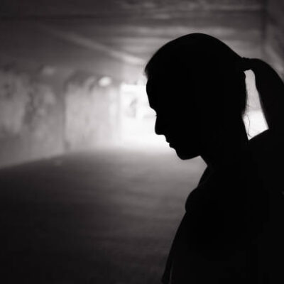 Depressed sad young female standing in a dark tunnel