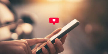 Close up woman hand hold using smart phone with heart icon at outdoor park street background. Copy space of technology business and travel holiday concept. Vintage tone filter effect color style.