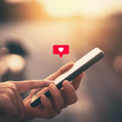 Close up woman hand hold using smart phone with heart icon at outdoor park street background. Copy space of technology business and travel holiday concept. Vintage tone filter effect color style.