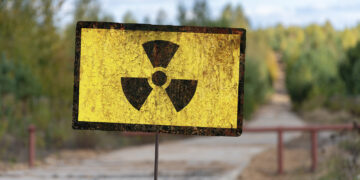 A sign of radioactive danger against the background of a forest yellowed by radiation. Concept: radioactive hazard, impact on nature, radiation dose.