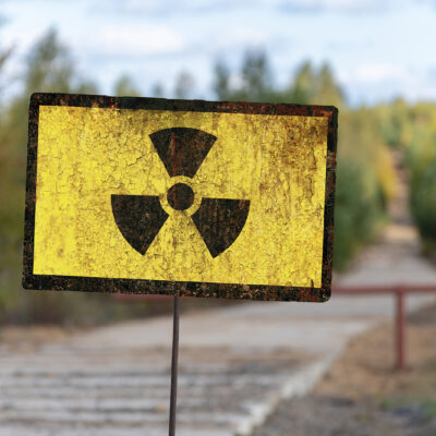 A sign of radioactive danger against the background of a forest yellowed by radiation. Concept: radioactive hazard, impact on nature, radiation dose.
