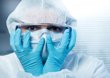Terrified scientist head in hands wearing hazmat protective suit.