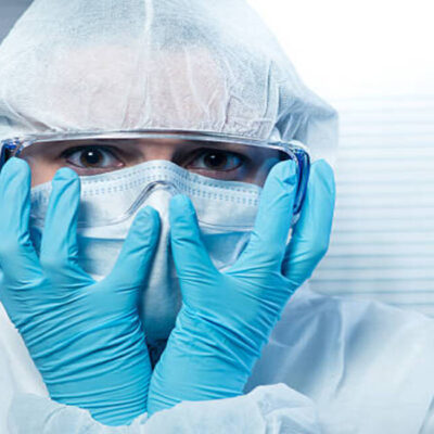Terrified scientist head in hands wearing hazmat protective suit.