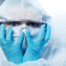 Terrified scientist head in hands wearing hazmat protective suit.