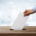 Ballot box with person casting vote on blank voting slip