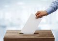 Ballot box with person casting vote on blank voting slip