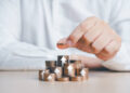 Saving money concept. Businessman hand putting a coin on top of stacked growing coins with percentage and arrow up icons. Future plan and financial management idea. Income managing, money planning.