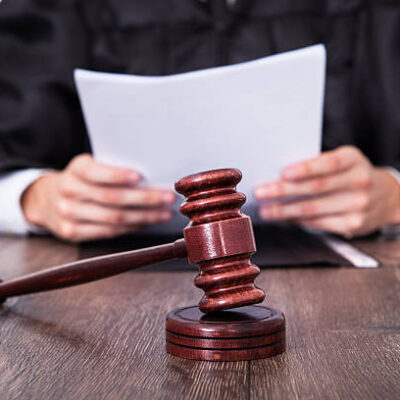 Close-up Of Male Judge In Front Of Mallet Holding Documents