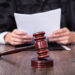 Close-up Of Male Judge In Front Of Mallet Holding Documents