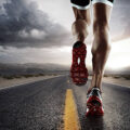 low angle view of male runners legs running down road wearing trainers