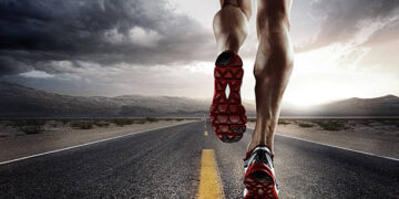 low angle view of male runners legs running down road wearing trainers