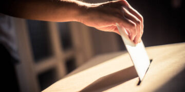 Conceptual image of a person voting, casting a ballot at a polling station, during elections.