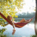 Woman relaxing on hammock by the river at sunset.