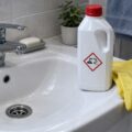 Средство для прочистки труб и защитные перчатки возле раковины. Иллюстрация создана с помощью ИИ.
