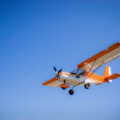 light single private orange plane in clear blue sky