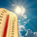 climate change, low angle view Thermometer on blue sky with sun shining in summer show increase temperature, concept global warming