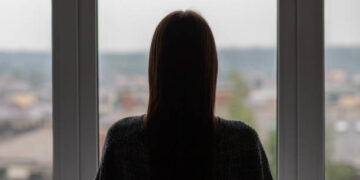 teenager anxiety,young woman is standing at the window, depression and frustration, an unhappy, sad girl