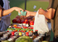 Farmer at market hands purchase to customer over colorful blend of organic produce