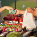 Farmer at market hands purchase to customer over colorful blend of organic produce