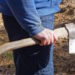 one male worker in blue clothes holds a gray ax in his hand on the street