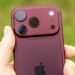 Смартфон iPhone в бордовом корпусе в руке
