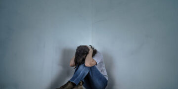 upset girl sitting in the corner of the room