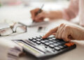 Pension calculation concept, old hands counting finances on a home calculator ,