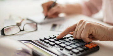 Pension calculation concept, old hands counting finances on a home calculator ,
