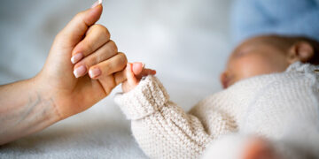 Close-up of mother's hand holding newborn baby's hand