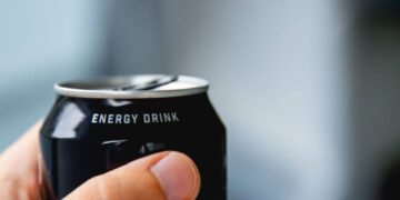 close up of a hand holding a can of energy drink
