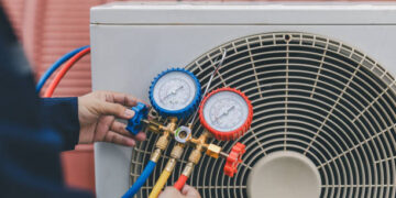 Technician is checking air conditioner. Air conditioning, HVAC service technician using gauges to check refrigerant and add refrigerant.
