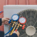 Technician is checking air conditioner. Air conditioning, HVAC service technician using gauges to check refrigerant and add refrigerant.