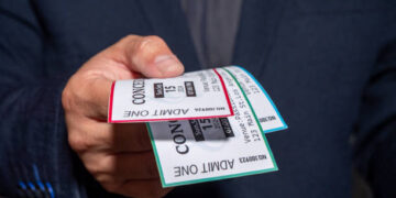A man is engaged in ticket scalping, selling concert tickets at a significantly higher price than face value