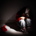 young girl sitting down alone in the dark.