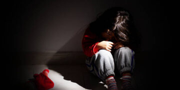 young girl sitting down alone in the dark.