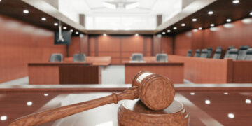Interior of an empty courtroom with gavel and sounding block on the desk.