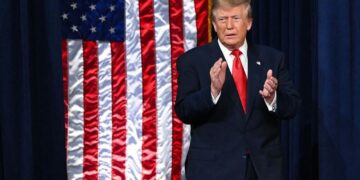 Дональд Трамп выступает на фоне флагов США